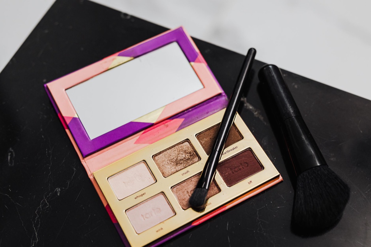 Primer plano de brochas de maquillaje y paleta de sombras