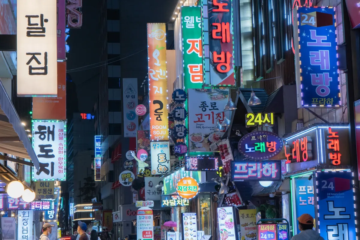 서울 대표 상업가의 바쁜 밤거리, 레이저 스티커와 화려한 도시 조명이 어우러진 모습.