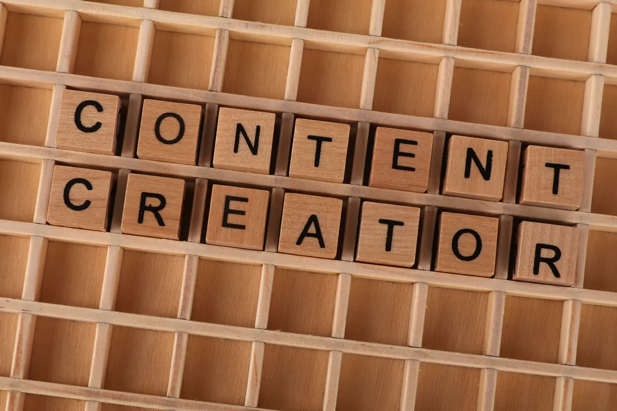 Wooden block letters spelling 'Content Creator' on a grid background. Ideal for digital marketing themes.