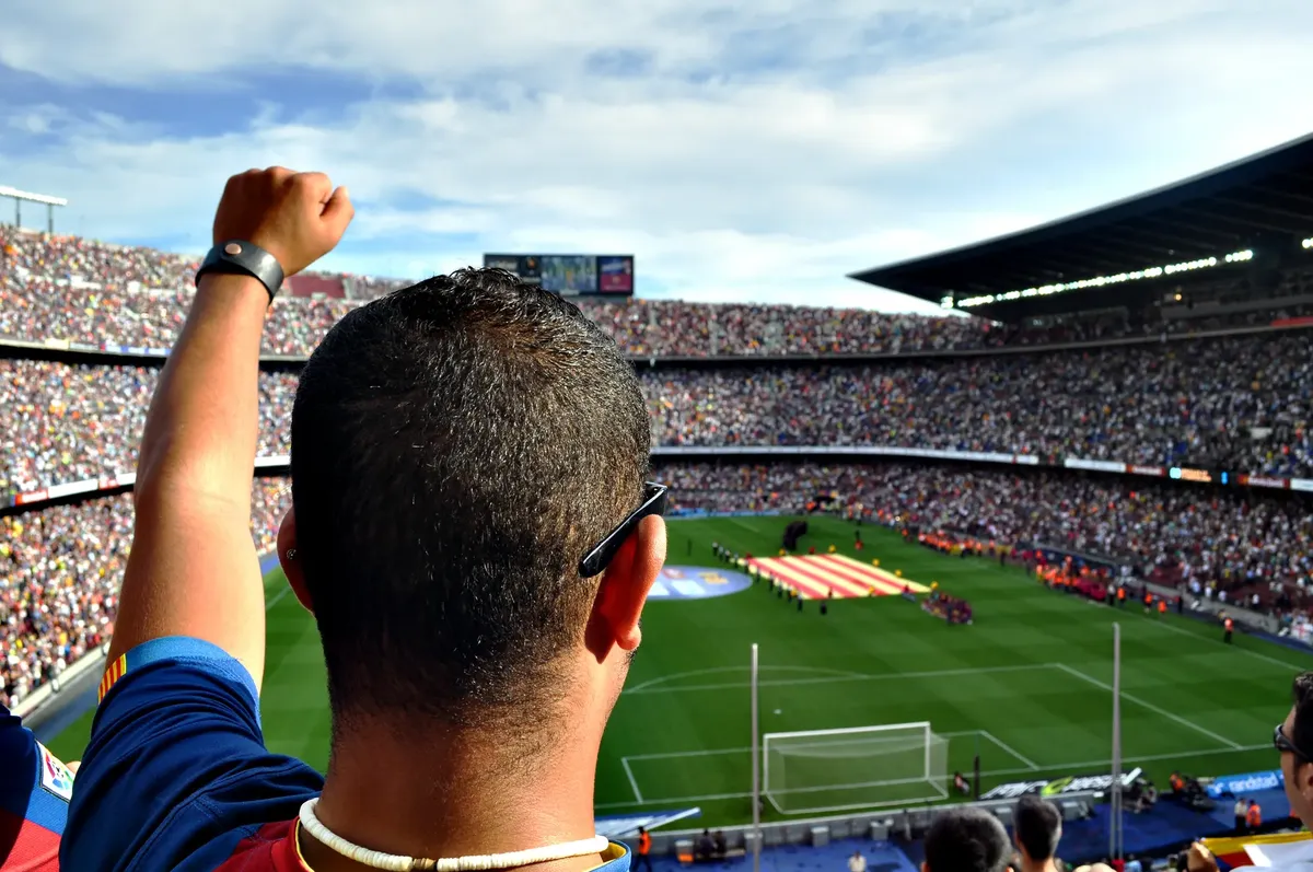 熱心なサッカーファンがにぎわうスタジアムの観客席で cheers している