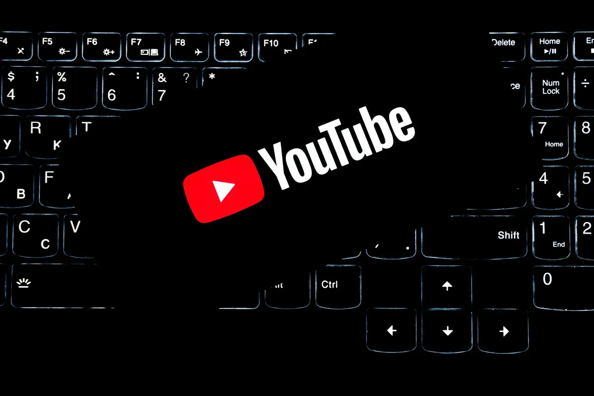 キーボードの後方照明が見えるYouTubeロゴ。デジタルメディアとオンラインコンテンツ作成を表している。