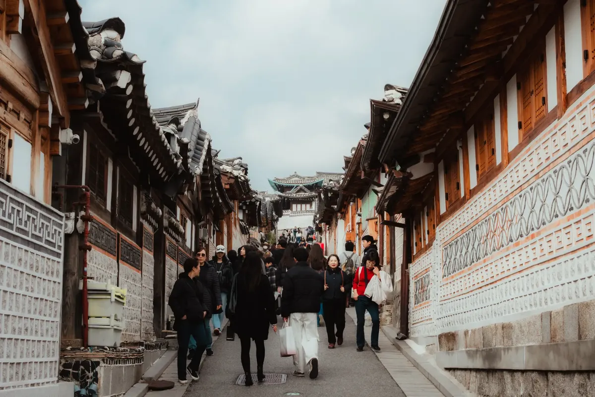 Crowds explore traditional architecture in Bukchon Hanok Village, Seoul, Korea.