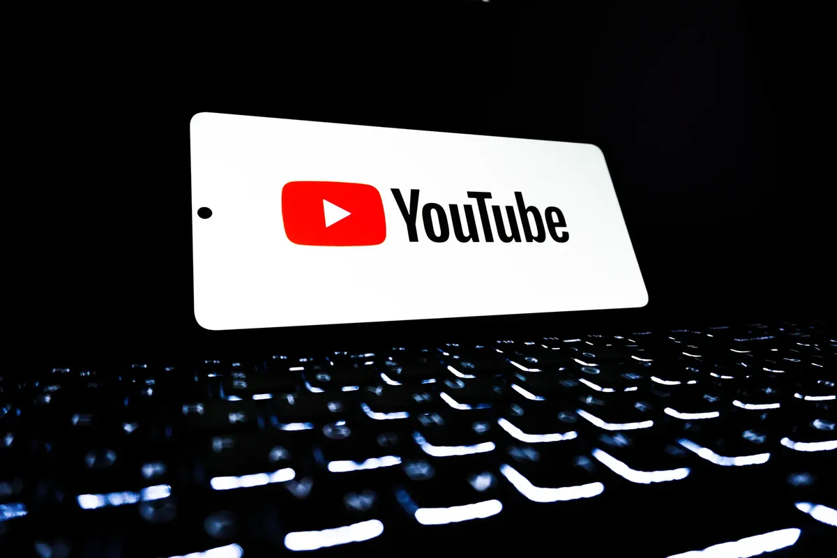 YouTube 앱 아이콘은 밝은 키보드 위의 스마트폰에 표시되어 있으며, 디지털 미디어 및 온라인 스트리밍을 상징합니다.